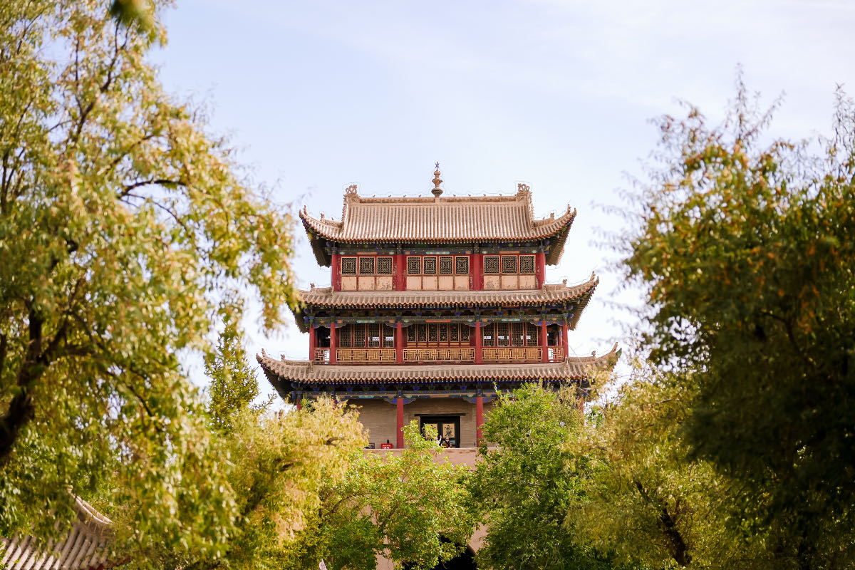 Una torre della fortezza di Jiayuguan tra gli alberi