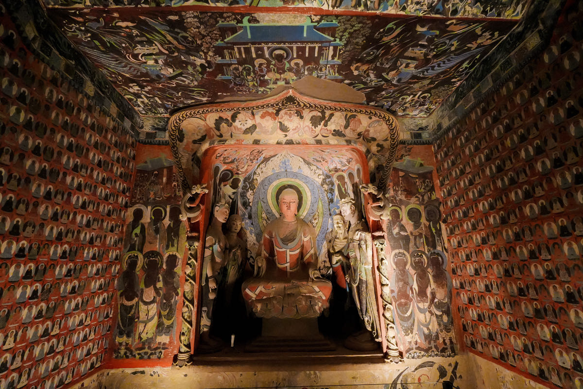 Grotte di Mogao a Dunhuang: guida completa alla visita 5 Riproduzione di una grotta di Mogao con il Buddha seduto e le pareti affrescate